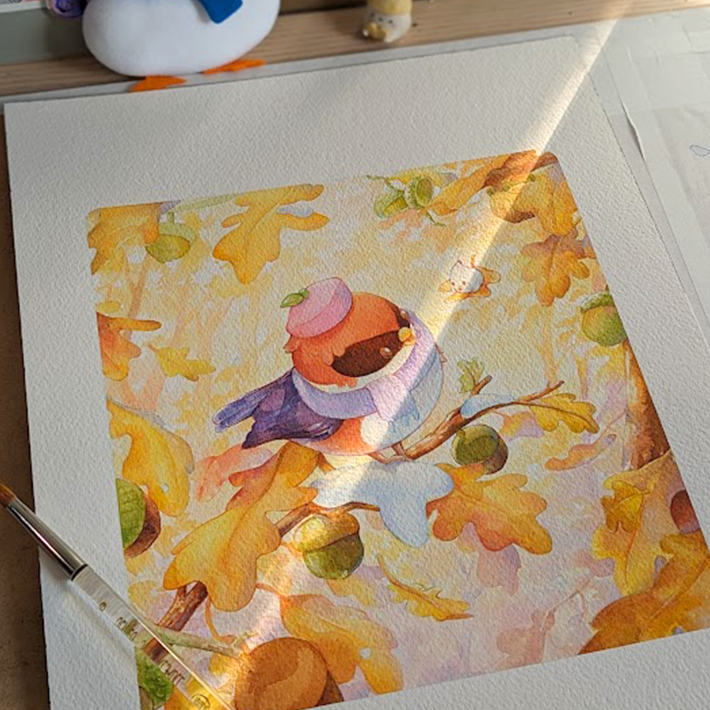 Autumn Bird displayed on a wooden table. A small Robin sits on a branch, surrounded by autumn colored leaves with a small patch of snow. Watercolor painting print