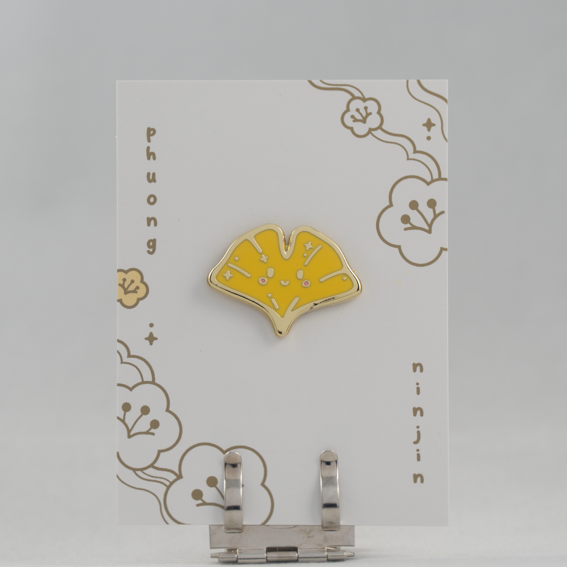 Ginkgo enamel pin with golden edge. Displayed here on our back card.