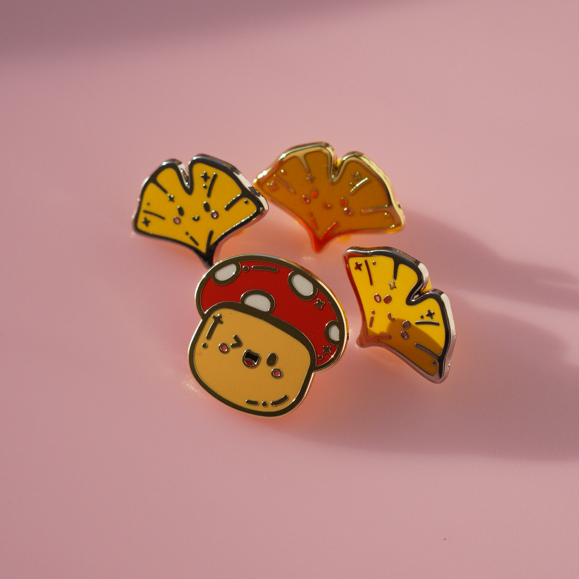 Autumn Mushroom enamel pin with golden edges, surrounded by our ginkgo enamel pins