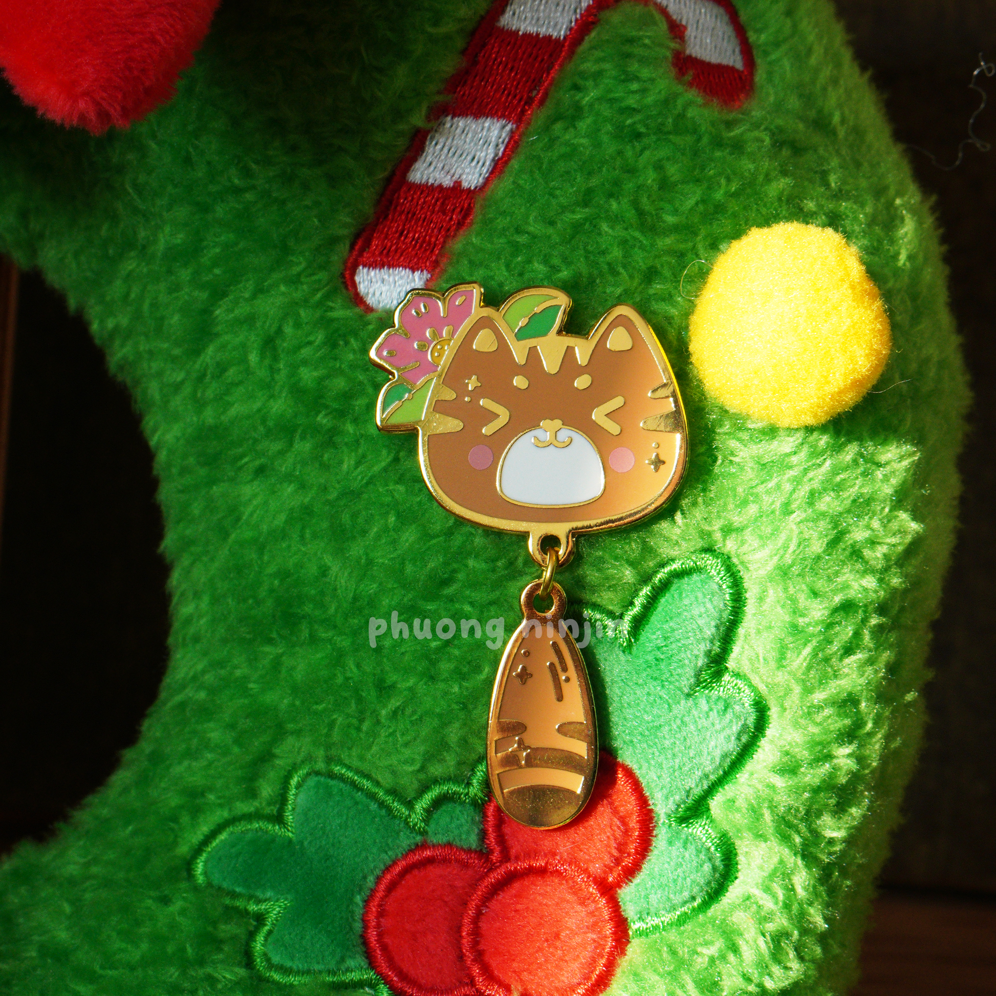 Momo cat enamel pin with golden edges. Displayed on some fluffy Christmas decoration
