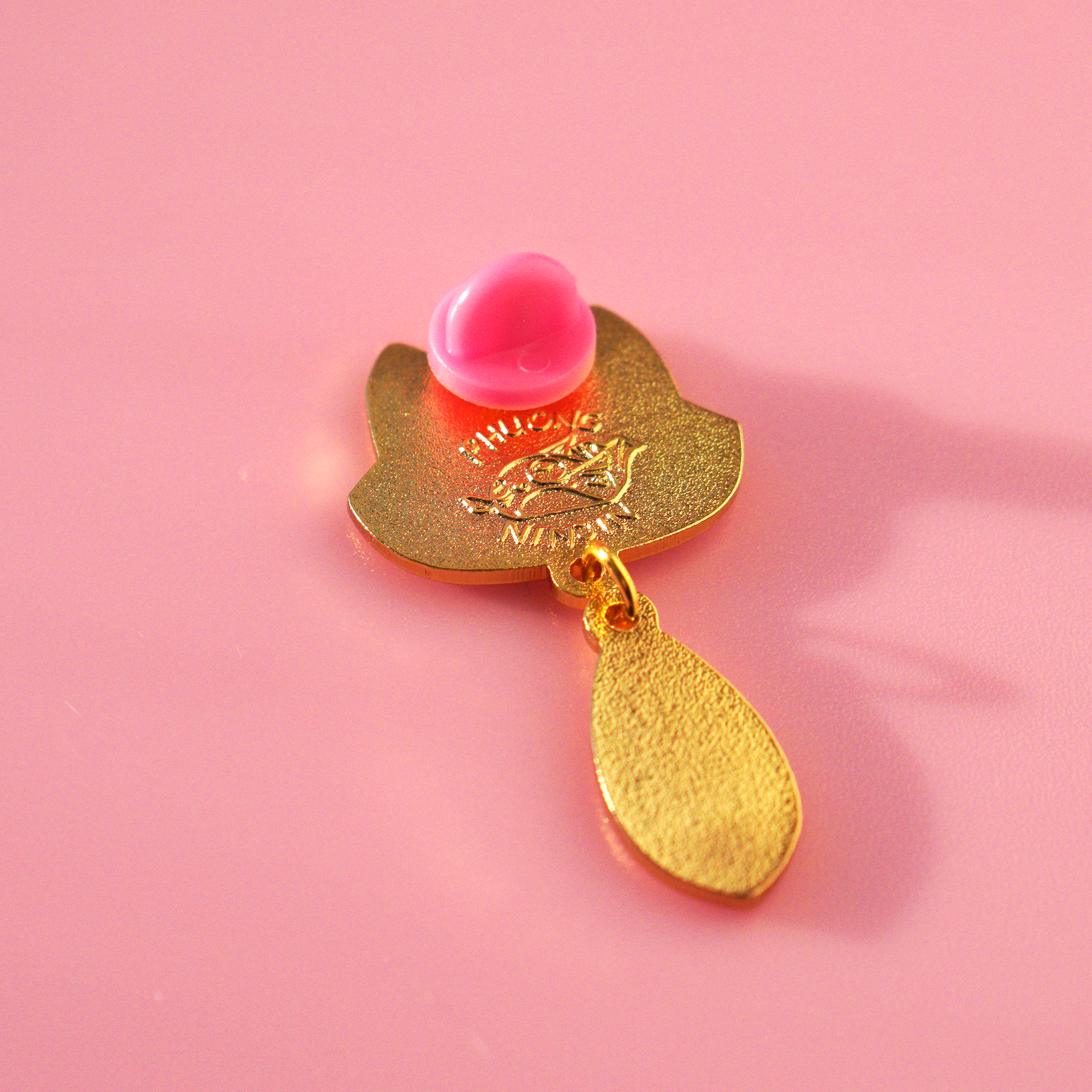Fox enamel pin with golden outlines. Displayed here from the back. Revealing the phuong ninjin logo embossed.
