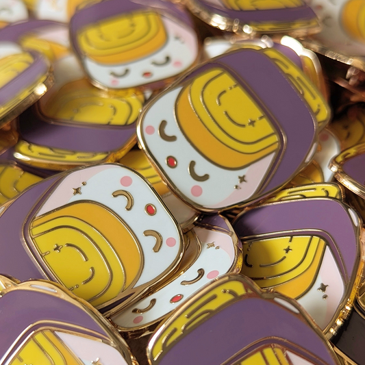 Sushi egg nigiri roll enamel pin with golden edges. Displayed here in a pile