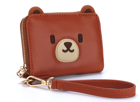 Bear shape wallet or purse. Made from vegan PU leather. Cute bear ears in silicone and face. We're shown a diagonal front view showing the wrist strap and cute face design