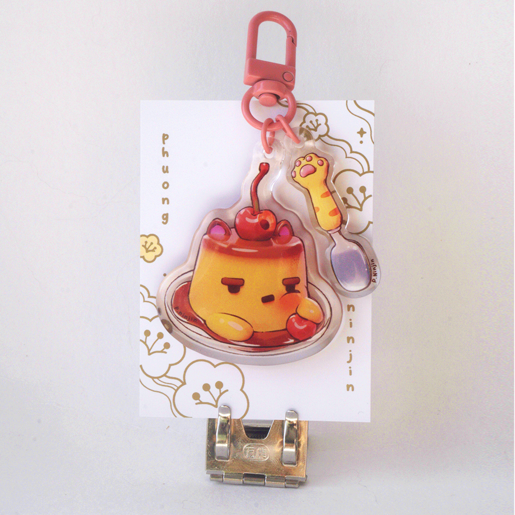 Dual sided flan keychain with cat ears and cherry on top. Along side a cat paw spoon. This side is showing the tooth ace side.