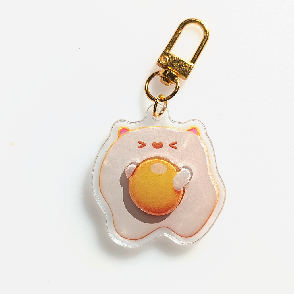 Egg keychain with >.< face and cute cat ears. The keychain has a 3D yolk. And Golden clamp