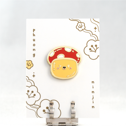 Autumn Mushroom enamel pin with golden edges, displayed on our back card